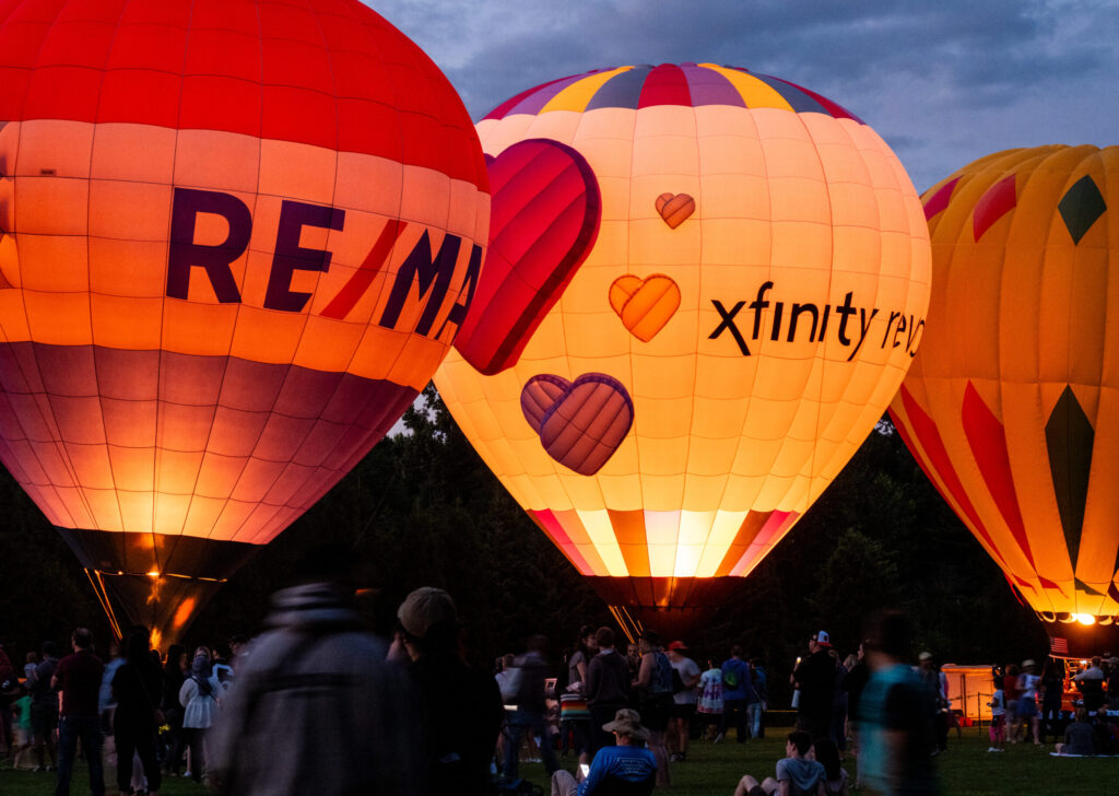 a set of three hot hair balloons are lit up from inside by the igniters below.